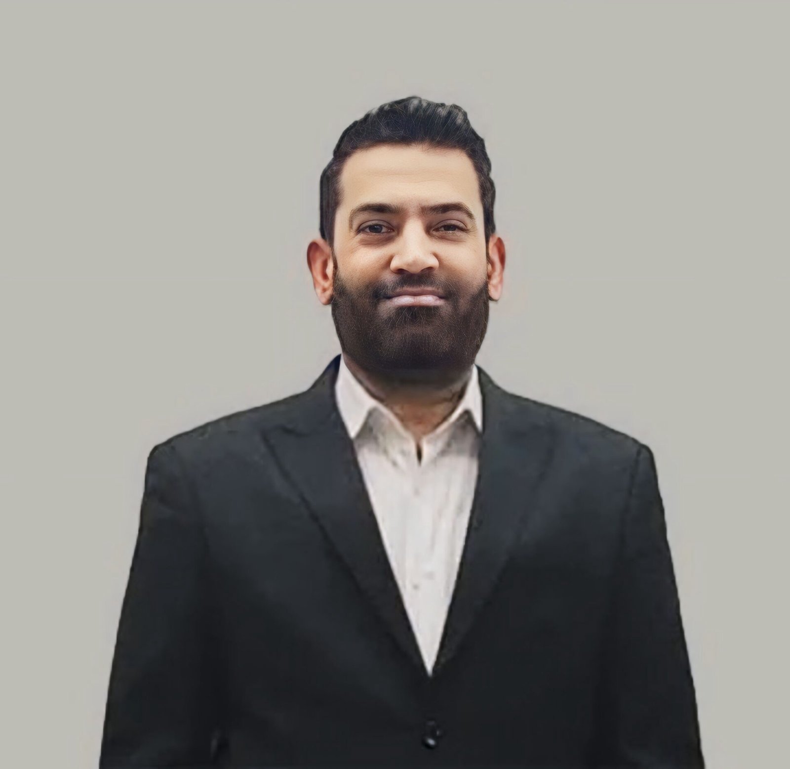 Professional business portrait of senior male executive wearing black suit jacket and white dress shirt against neutral gray background for team profile on company about page